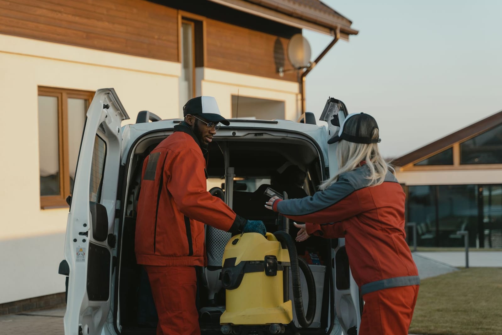 Technicians loading equipment from a service van outside a home at the start of a call